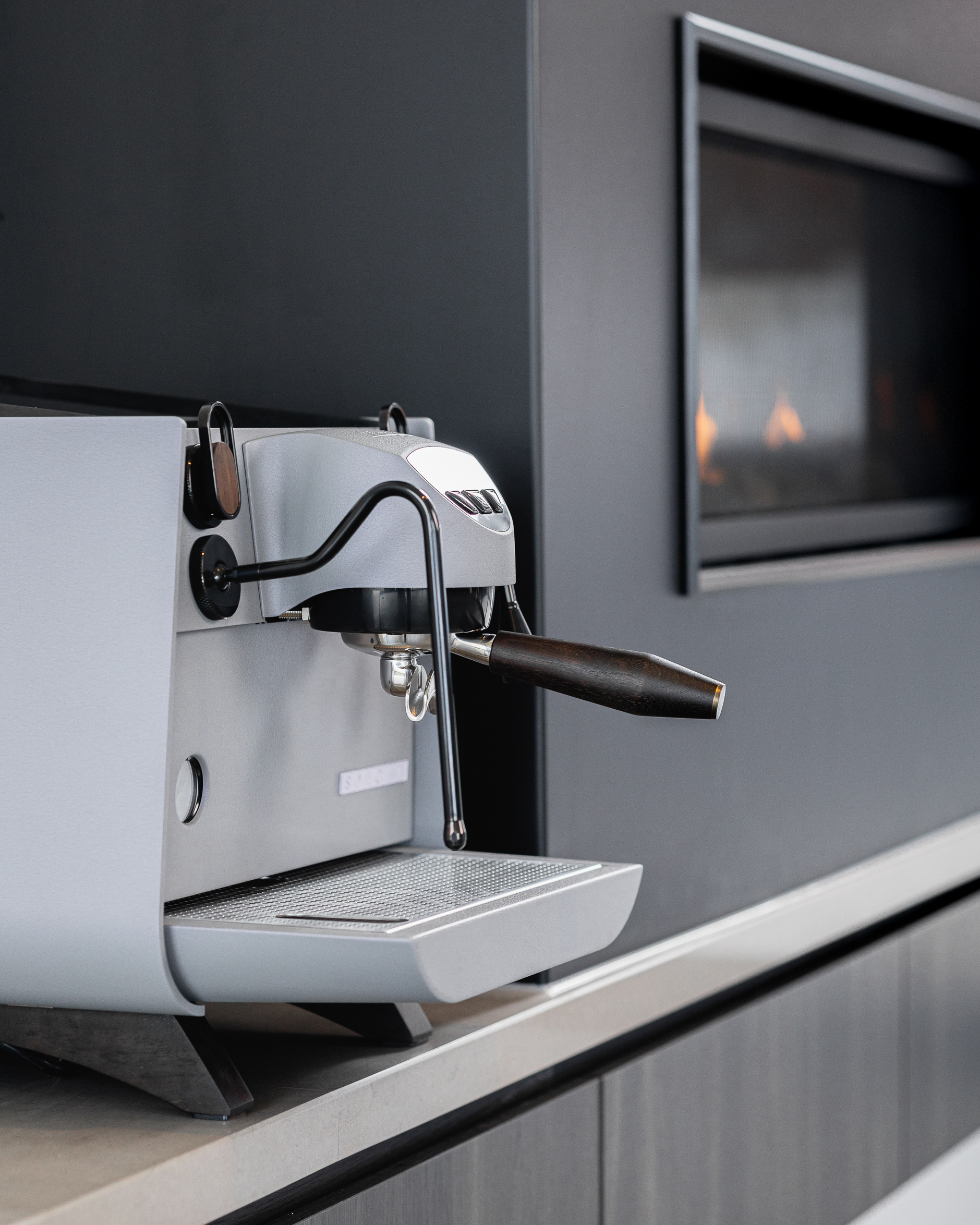 A side view of the walnut portafilter handle of Lavender Haze by Specht, a purple-grey Victoria Arduino Eagle One Prima EXP espresso machine.