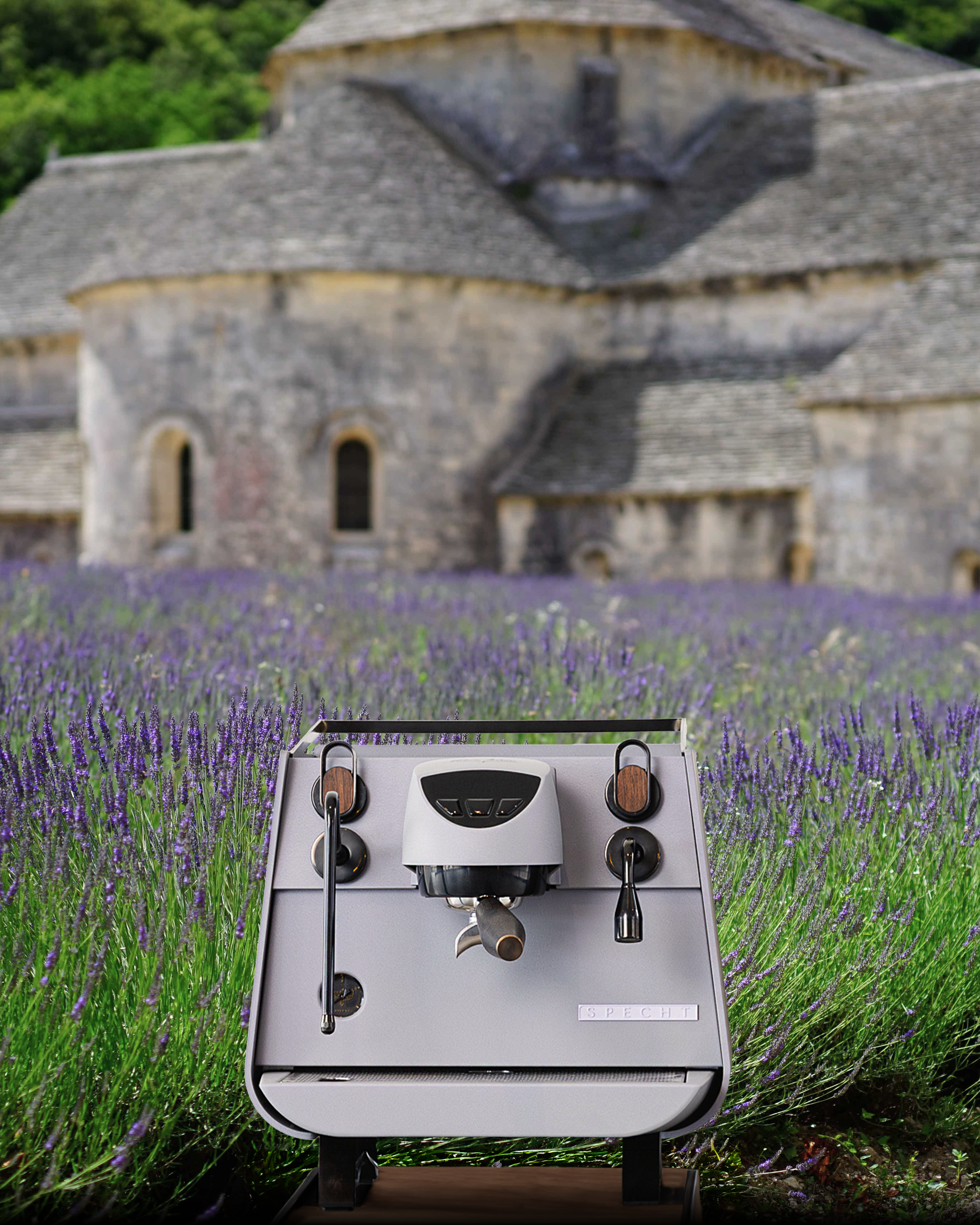 A front view of Lavender Haze by Specht, a purple-grey Victoria Arduino Eagle One Prima EXP espresso machine. A limestone Abbey and field of lavender lies behind it.