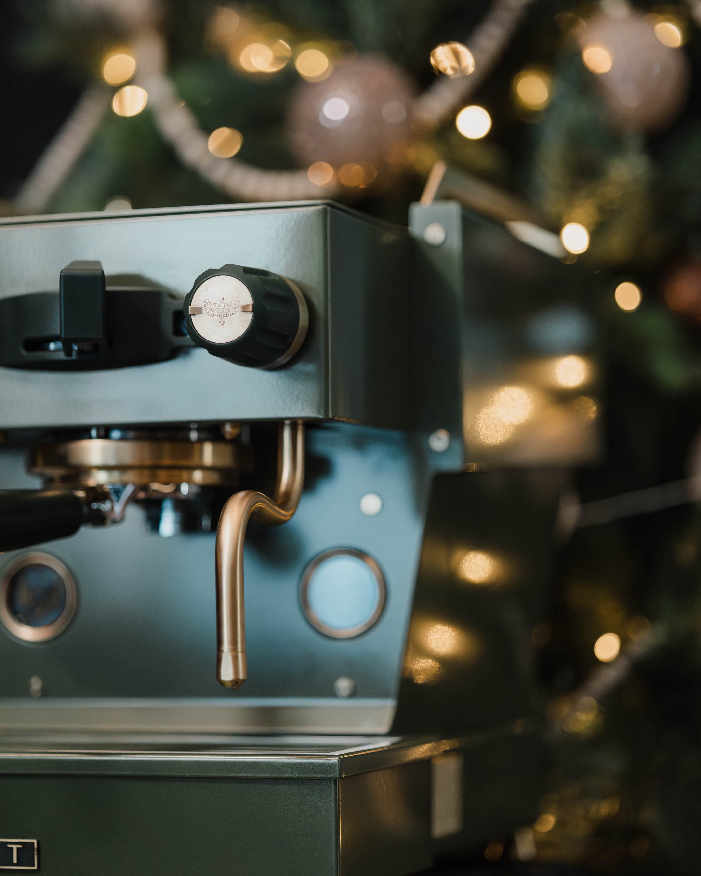 A close-up of The Pickle, a deep green Linea Micra with brass-gold accents, showcasing the Specht bird logo on its steam knobs.