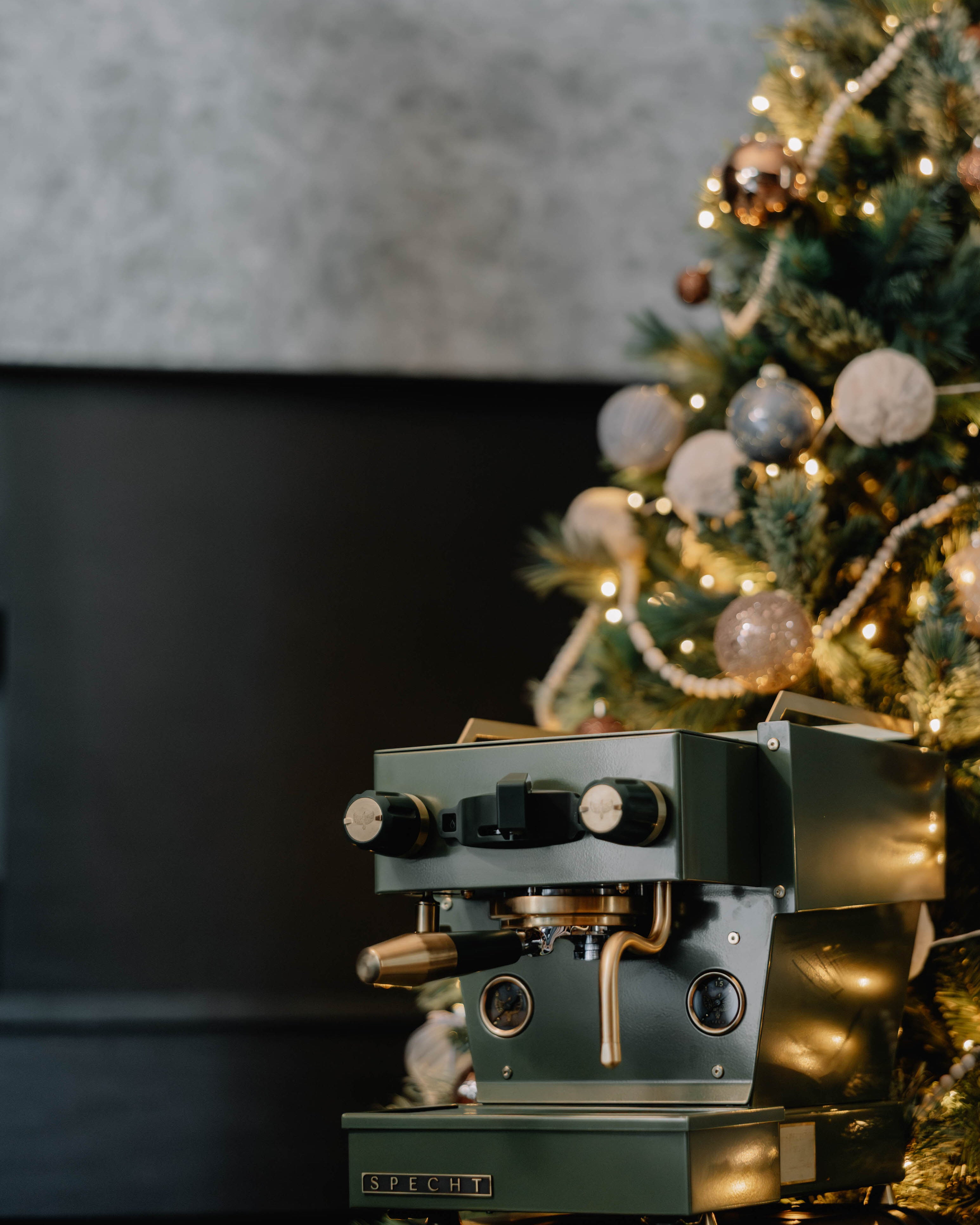 A dark green Linea Micra with brass highlights, underneath a Christmas tree.