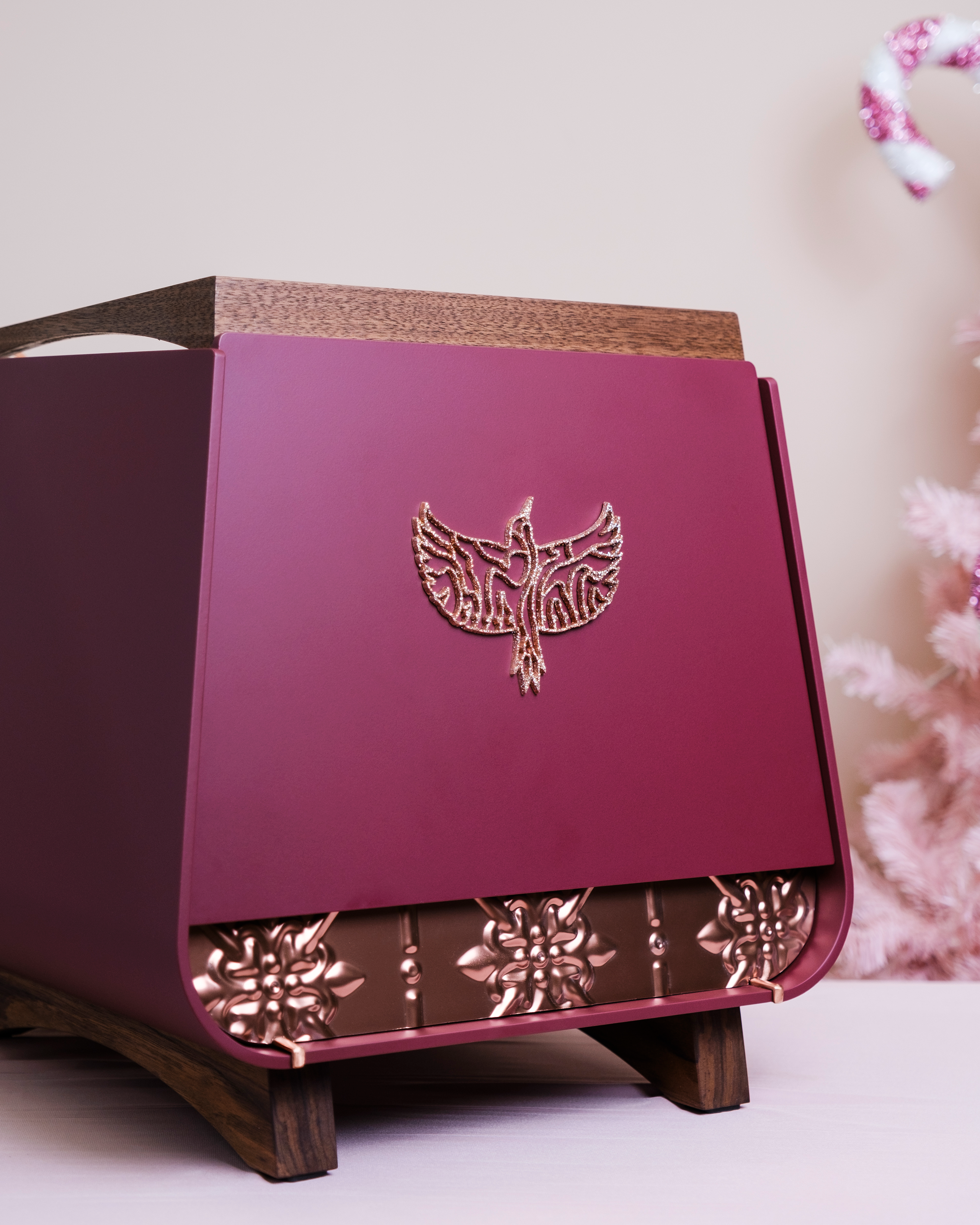 The back of a pink and burgundy Eagle One Prima EXP home espresso machine, reimagined by Specht with walnut and copper touchpoints. A large Specht logo and ornate metal feature are displayed prominently.