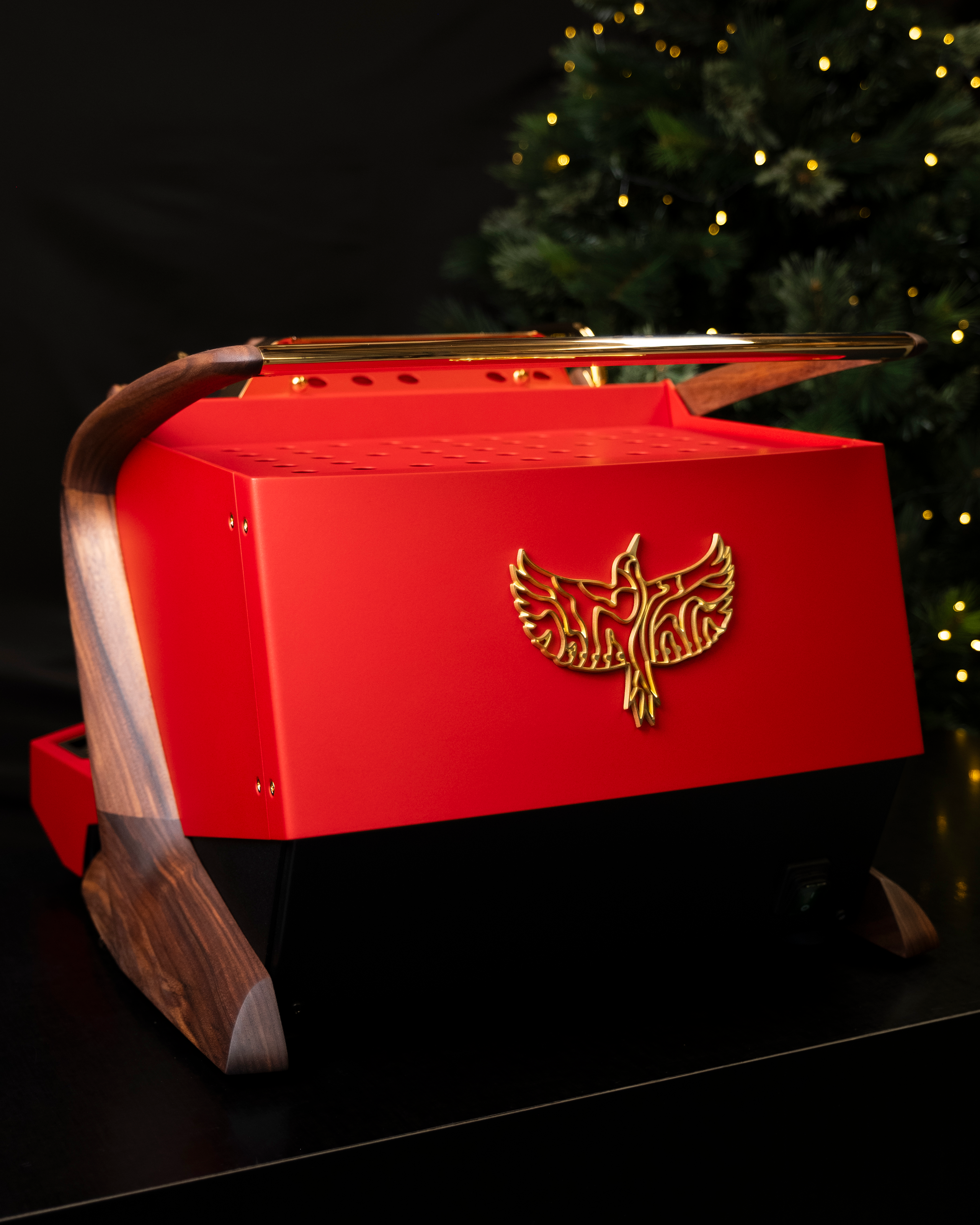 The back of a red, gold-plated Slayer Steam Single espresso machine with walnut legs, showcasing a brass Specht logo.