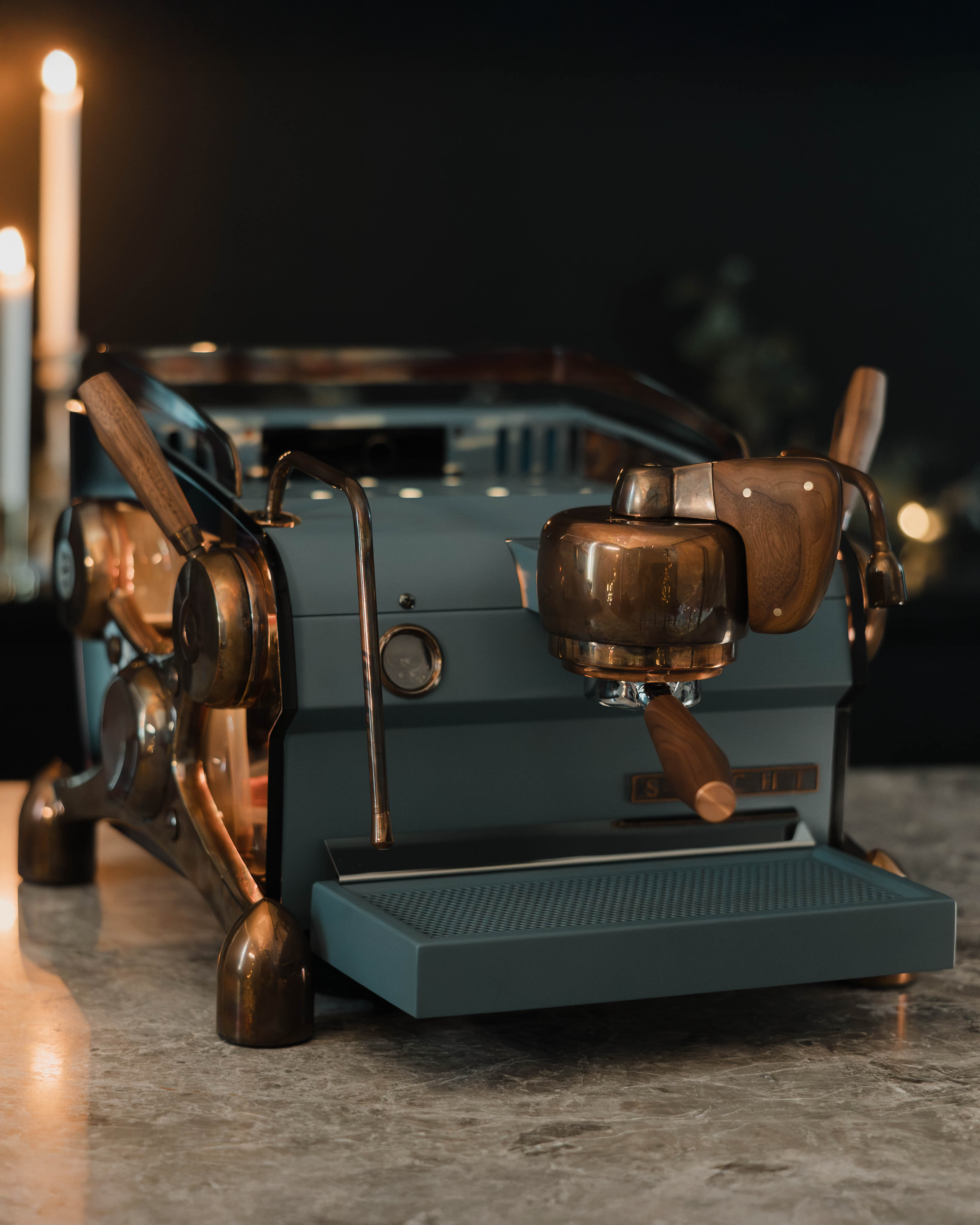 A deep blue, bespoke Slayer Single Group espresso machine with burnt copper highlights, walnut accents and backlit, smoked transparent side panels.