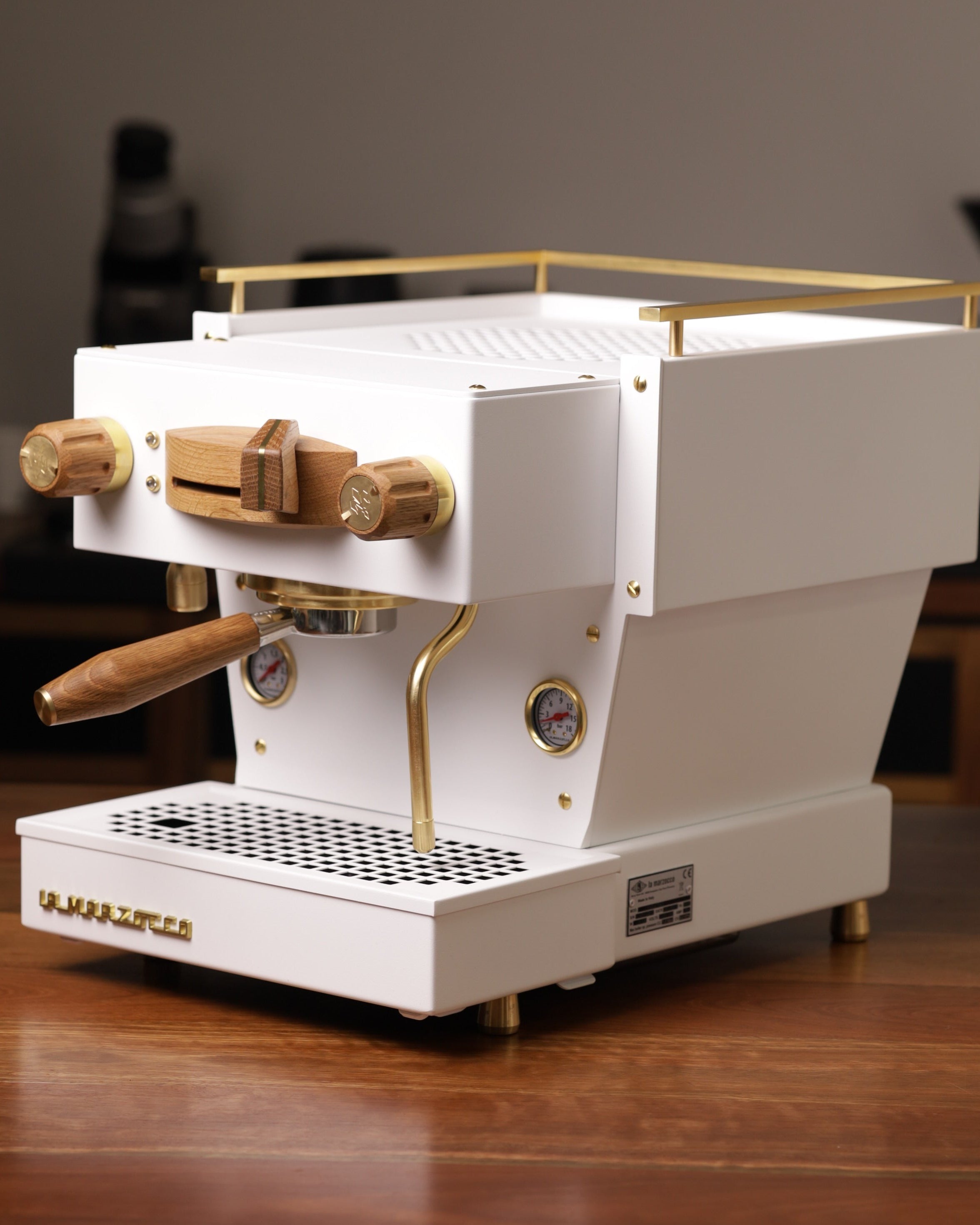 A white, Specht La Marzocco Linea Mini espresso machine with polished brass and oak wood accents.
