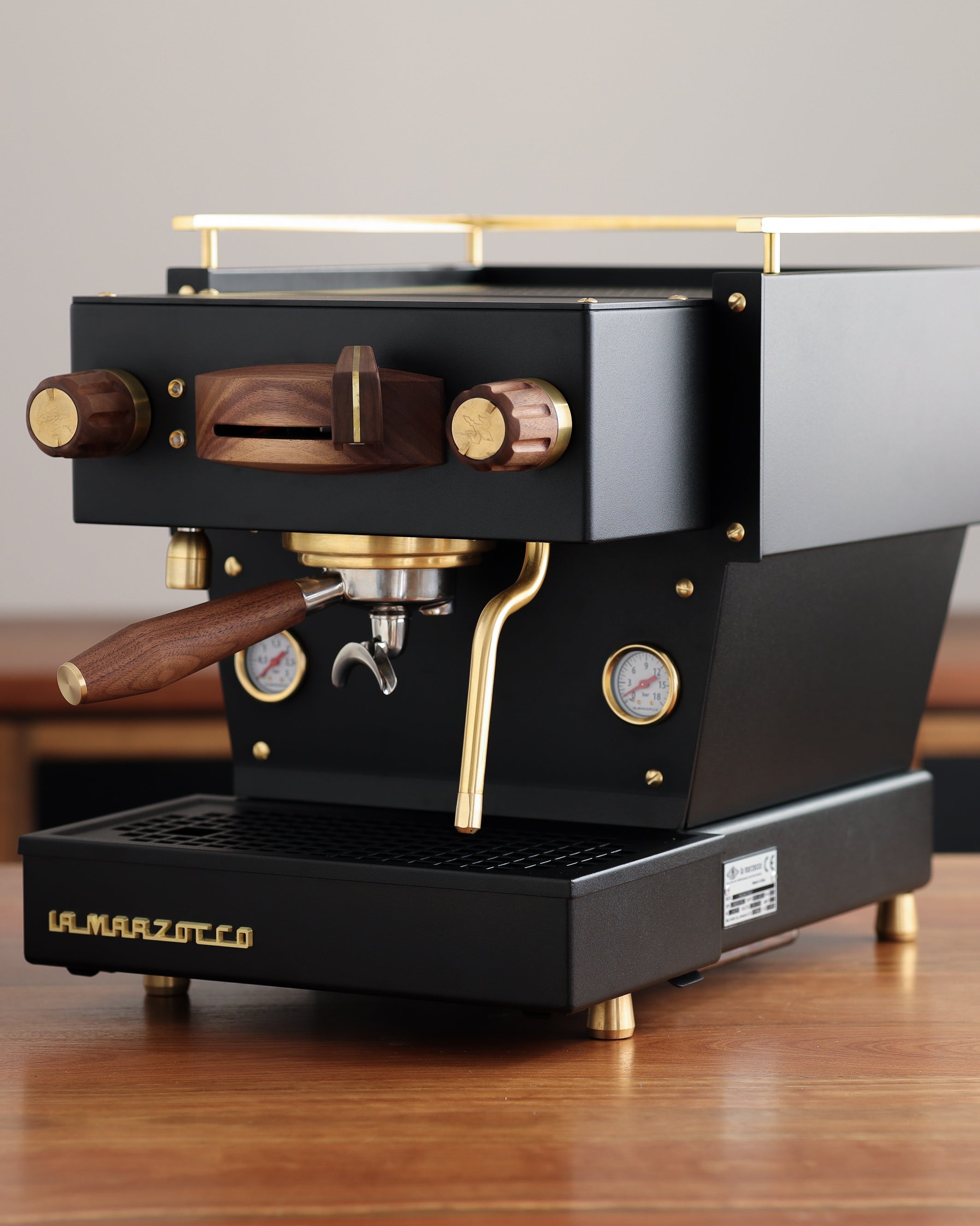 A black, Specht La Marzocco Linea Mini espresso machine with polished brass and walnut wood accents.