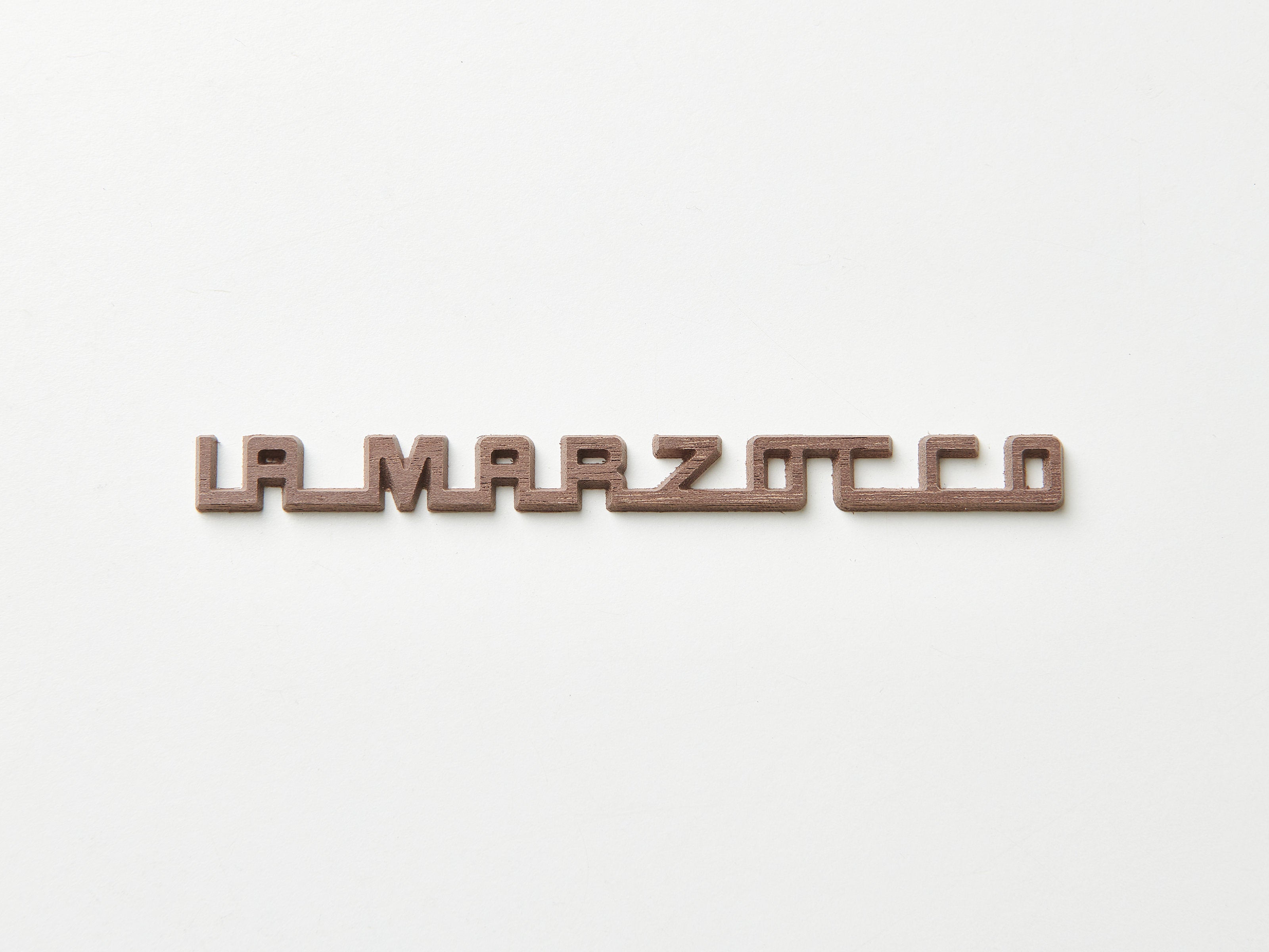 A dark walnut La Marzocco badge for espresso machines.