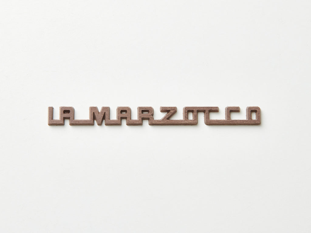 A dark walnut La Marzocco badge for espresso machines.