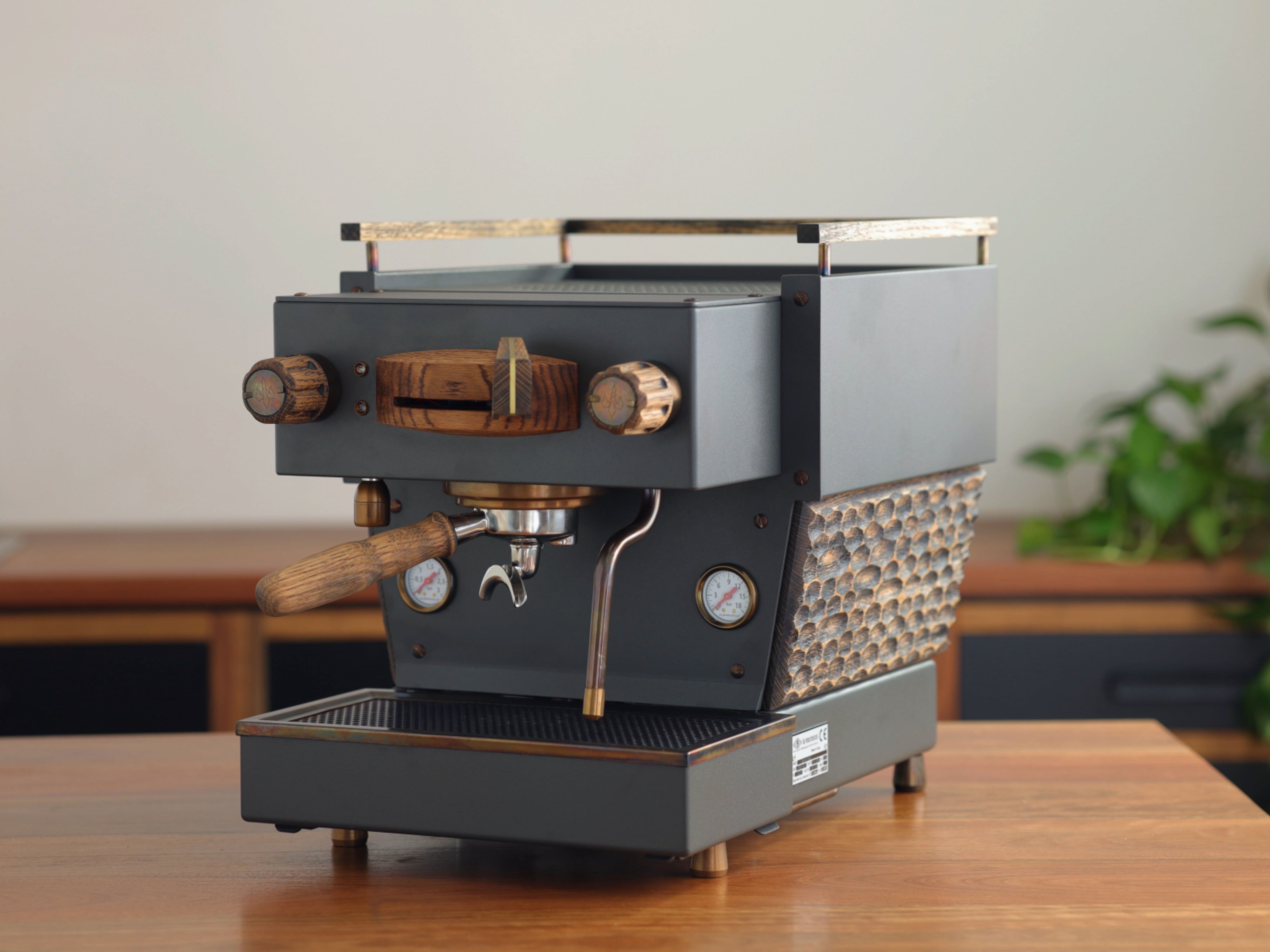 A weathered-slate grey Specht Linea Mini with a hand-carved, aged-oak mid-section, and bronze highlights.