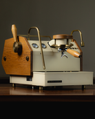An almond-white La Marzocco GS3 AV espresso machine, redesigned by Specht with stained oak and aged brass accents.