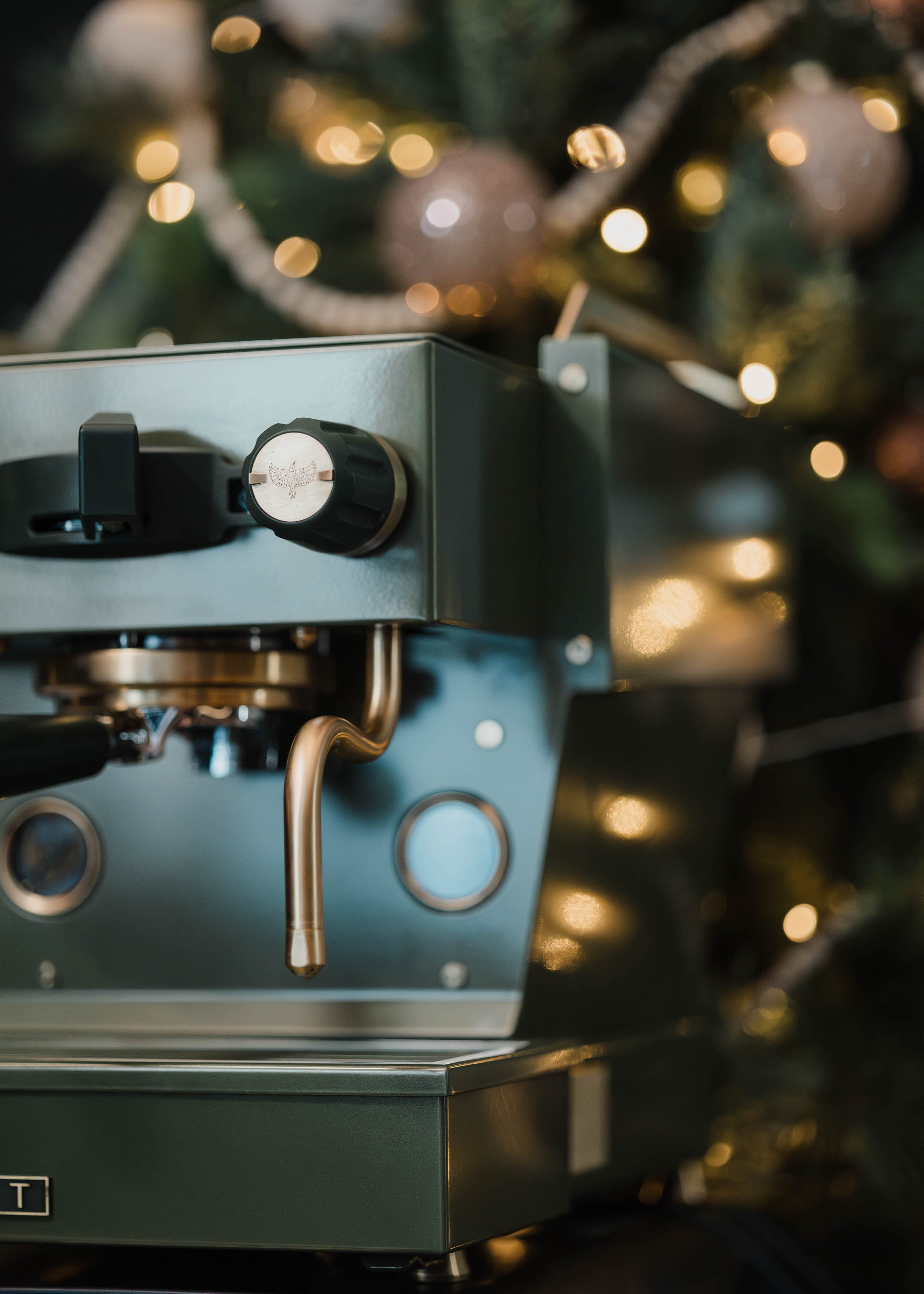 A close-up of The Pickle, a deep green Linea Micra with brass-gold accents, showcasing the Specht bird logo on its steam knobs.